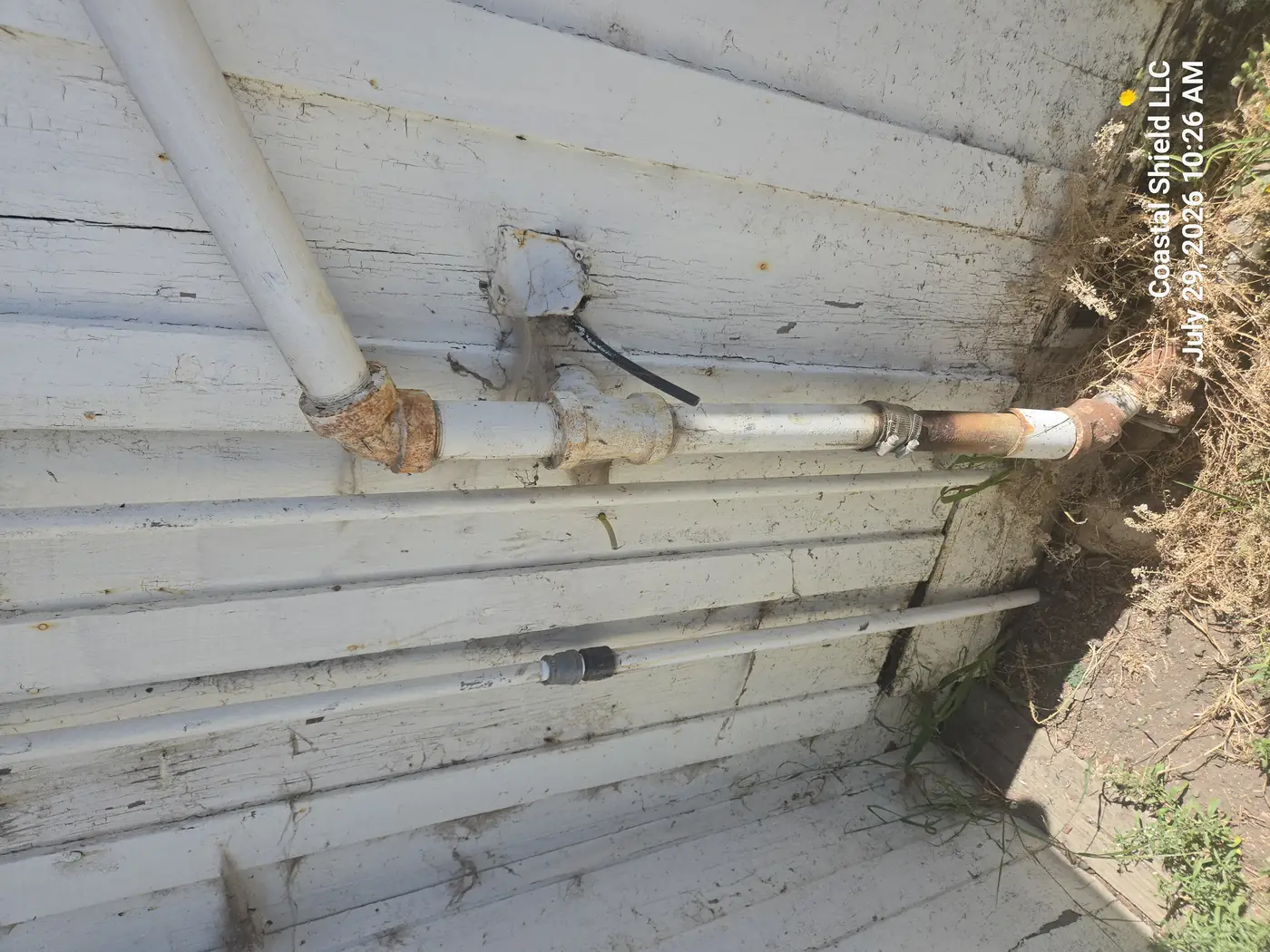 Surface-run galvanized water piping with heavy rust bleed at every fitting