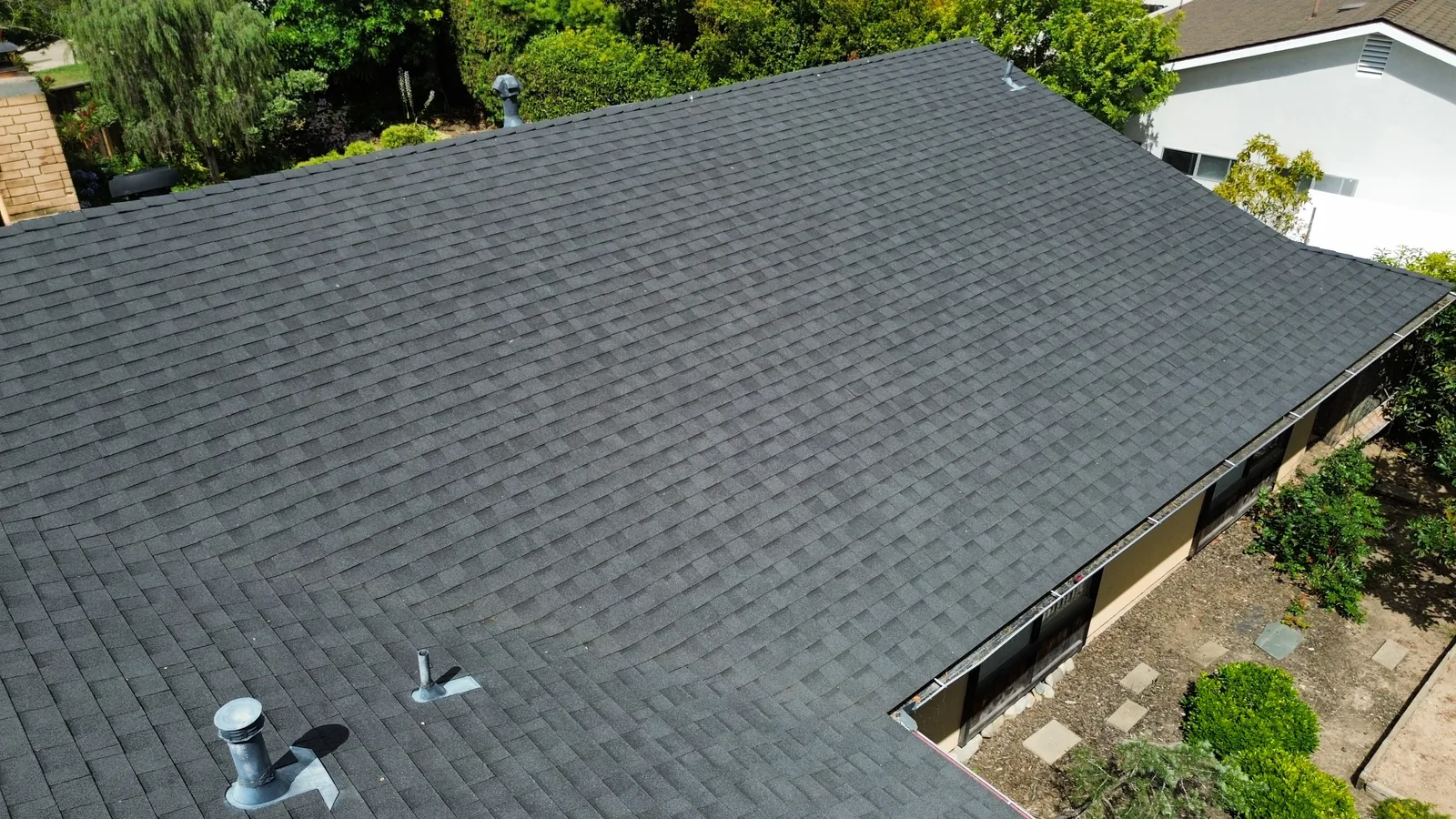 Aerial drone close-up of a roof ridge with pipe boots and metal flashing on a Santa Barbara home
